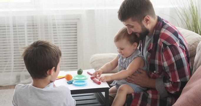 Father and children having fun playing with plasticine at home