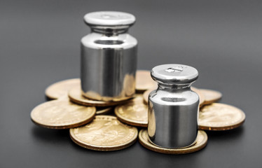 Weights with coins on black. Business concept. Tax load.