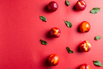 Nectarines and leaves on red background table