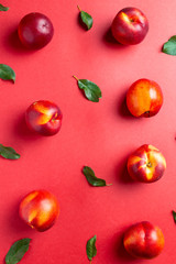 Nectarines and leaves on red background