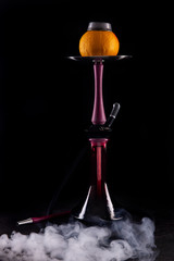 A hookah in the dark extended flask on a bowl with grapefruit