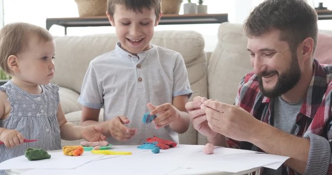 Happy father and children playing with plasticine at home
