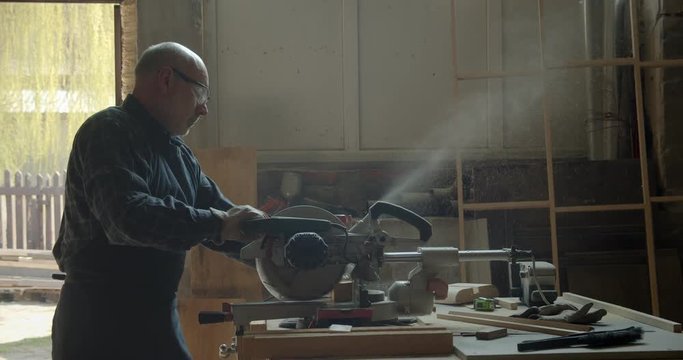 Portrait of male caucasian carpenter carving the wood with headsaw into small squares in manufacture.