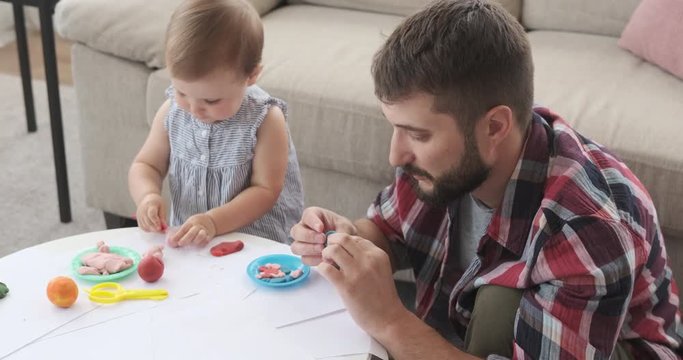 Father and baby daughter making shapes using plasticine at home