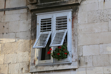 Fototapeta na wymiar The windows of the house with shutters and flowers