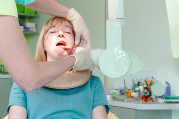 Dentist adjusting an digital X-ray of oral cavity while patient sitting on chair