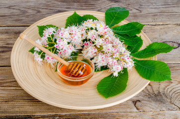 Delicious chestnut honey in glass on wooden surface.