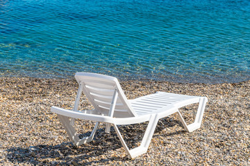 Fototapeta na wymiar Empty white plastic chaise lounge on the background of the sea