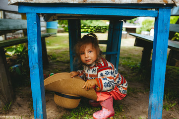 Obraz premium Child with a big straw hat in hands in rural style. Rural portrait