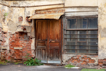 vintage courtyard of an old industrial building with a closed wooden door. collapsing facade 