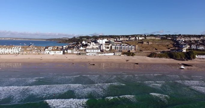 Aerial view of sandy Porthmeor beach, seafront promenade in a coastal English town of St Ives, south west corner of United Kingdom, Cornwall, on a summer day .
