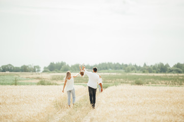 Happy family walk in wheat field on sunny day