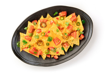 Nachos on a white background. Mexican totopos, tortilla chips, shot from the top with a cheese sauce, chili and jalapeno peppers, tomatoes, and cilantro, on a white background