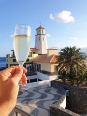lighthouse on beach with glass of champage in male's hand