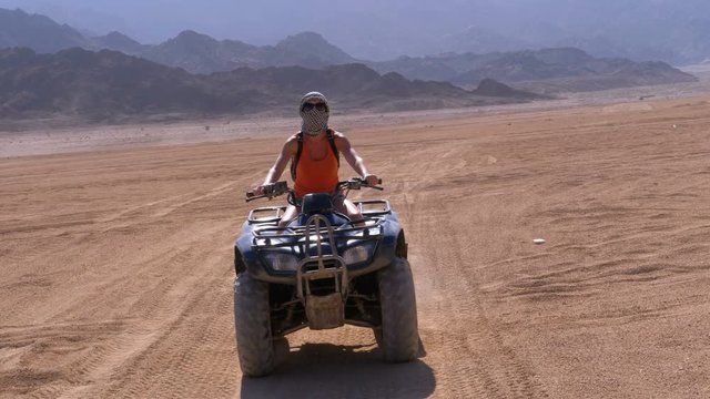 Sexy Girl on a Quad Bike Rides through the Desert of Egypt on Background of Mountains. Slow Motion