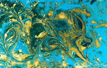 Liquid uneven blue and green marbling pattern with golden glitter and glare of light