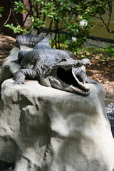 Plastic figurine of crocodile on stone.