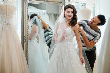 Naklejka premium Beautifu bride choosing wedding dress in a wedding salon