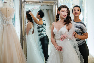 Beautifu bride choosing wedding dress in a wedding salon