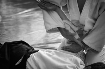 Black and white image of aikido. Hands of fighters. The traditional form of clothing in Aikido. Background image. No faces and recognizable elements