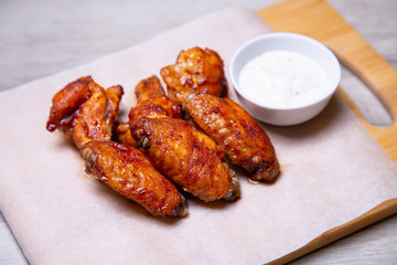 BBQ chicken wings with sauce on paper. Close-up, selective focus.