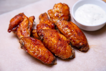 BBQ chicken wings with sauce on paper. Close-up, selective focus.