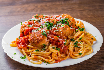 pasta spaghetti with meatballs in tomato sauce on a plate on dark wooden background