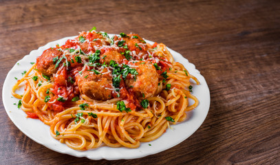 pasta spaghetti with meatballs in tomato sauce on a plate on dark wooden background