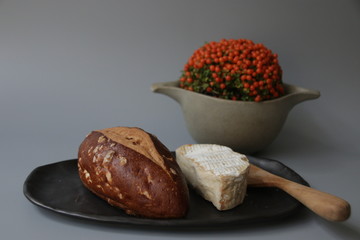 Breads in White Ceramic Bow and Traditional Cheese on Grey Background
