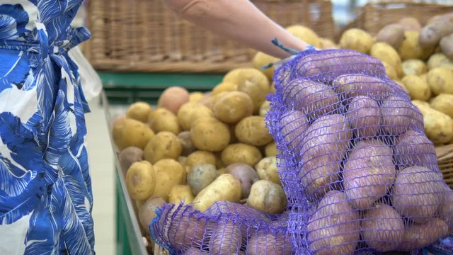 Social market concept, cheap products. woman picks potatoes in a grid on the counter in the store