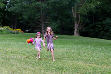 Naklejka premium Horizontal full length view of cute fair pre-teenager running in lawn with a small girl