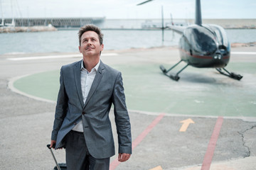 Businessman standing near private helicopter