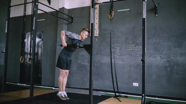Man does triceps dip exercise in gym on parallel bars or dip stantion. Athlete dressed in comfortable sportswear. Clothes are comfortable and absorb sweat. Muscular man doing bodyweight dips, strength