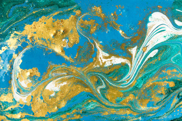Liquid uneven blue and green marbling pattern with golden glitter and glare of light