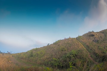 Mountain view of tourists walking on the hill with cloudy and blue sky background, Phu Chi Fa (Phu Chee Fah), Chiang Rai, Thailand.