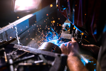 Worker welding a metal part using a machine with sparks. close-up.