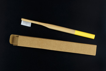 Eco-friendly bamboo toothbrush in paper packaging on a black background.Flat lay.Zero waste concept, conscious consumption