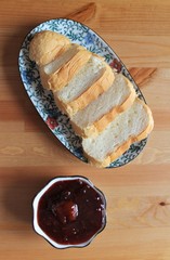 Slices of white bread on a plate on the table with plum jam