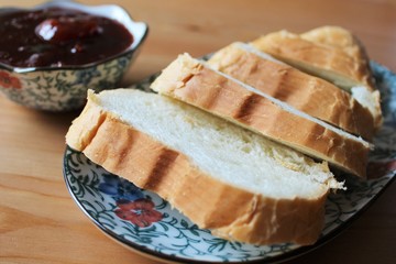 Slices of white bread on a plate on the table with plum jam