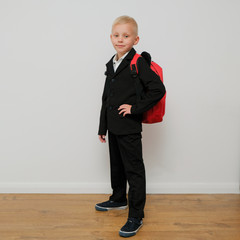 Stylish trendy little boy in a suit with a school back. Child from elementary school on white background