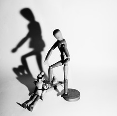 Violence and manipulation. The wooden puppet applies power and force, aggression to another figure. Concentration of violence in the family and society.