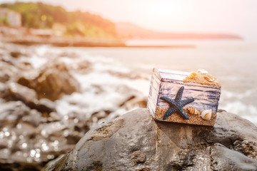 Wooden decorative Chest with sea shells and blue star on the sea coast.