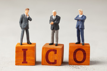 Businessmen and the word ICO and investments on a gray background.