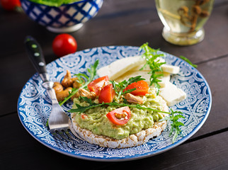 Healthy avocado toasts for breakfast or lunch,  avocado, arugula, tomatoes, cashew nuts, feta cheese and pepper. Vegetarian sandwiches.