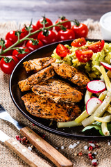 Grilled chicken fillet and vegetables on wooden table