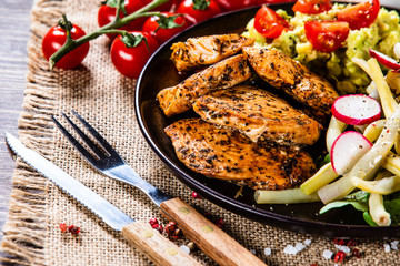 Grilled chicken fillet and vegetables on wooden table