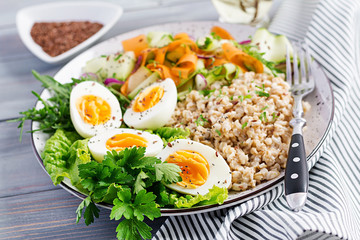 Breakfast bowl with oatmeal, zucchini, lettuce, carrot and boiled egg. Fresh salad. Healthy food. Vegetarian buddha bowl.