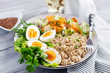 Breakfast bowl with oatmeal, zucchini, lettuce, carrot and boiled egg. Fresh salad. Healthy food. Vegetarian buddha bowl.