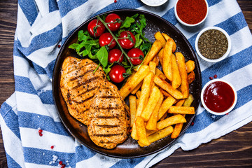 Grilled chicken fillet with french fries on wooden table