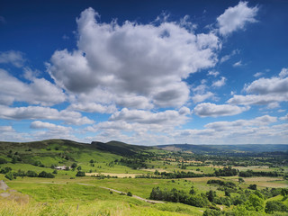 View over sunlit Hope Valley with Lose Hill in the background and billowing white clouds scudding across the deep blue sky, Peak District National Park, UK